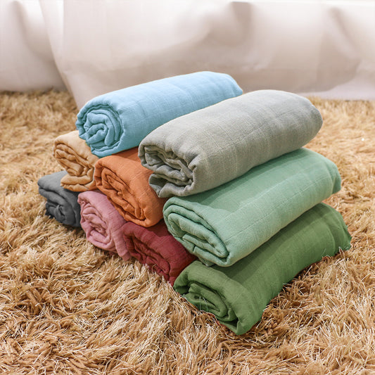 a stack of different coloured muslin swaddle blankets
