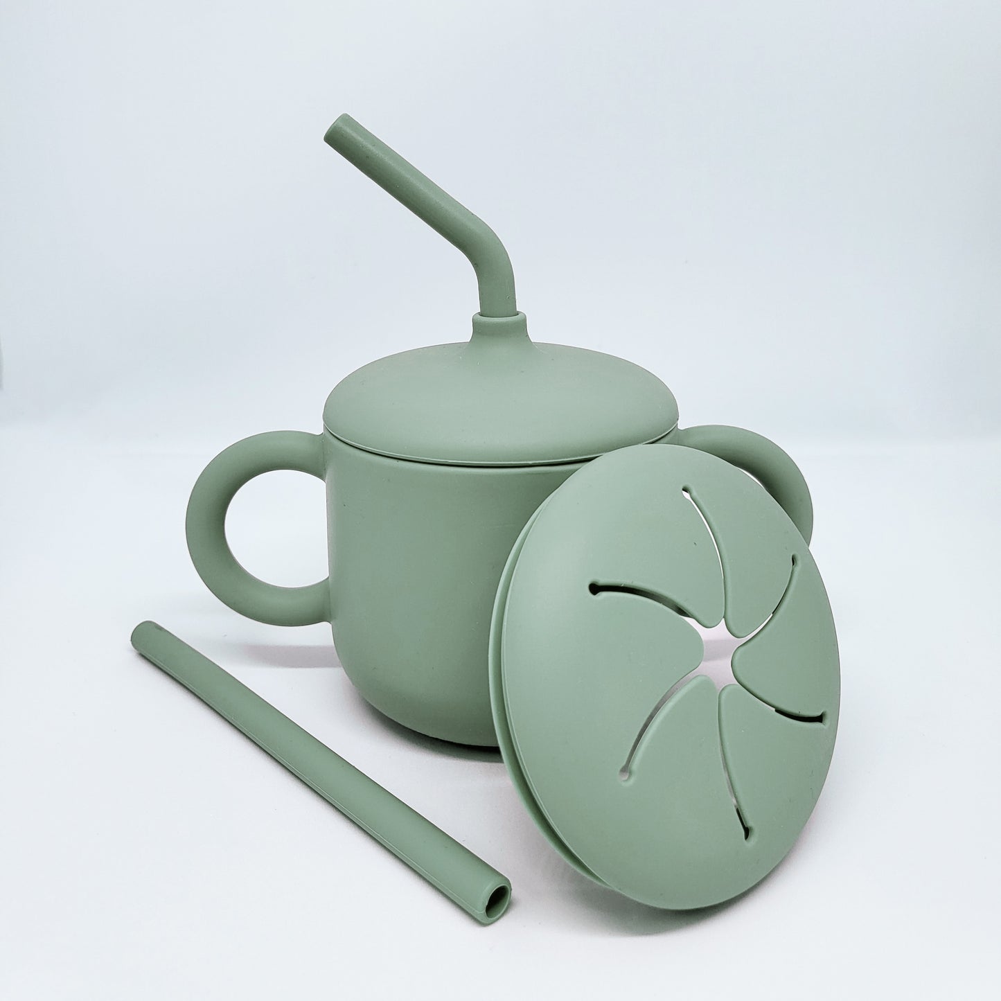 a green sippy cup with its snack cover and second straw next to it.