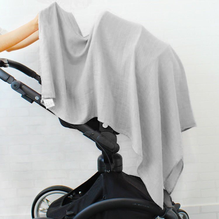 a grey muslin swaddle blanket draped over a baby stroller